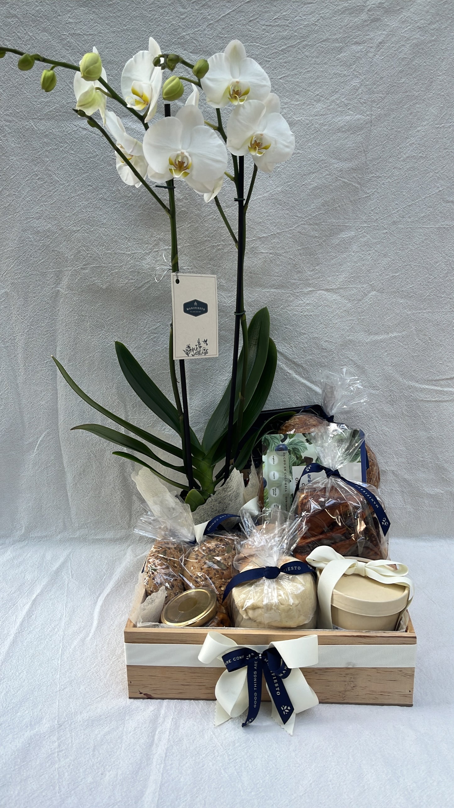 Regala una ancheta con orquídea, panes artesanales, queso local, jamones curados, conservas sin azúcar, brownies y arándanos con chocolate. Envíos en Medellín.