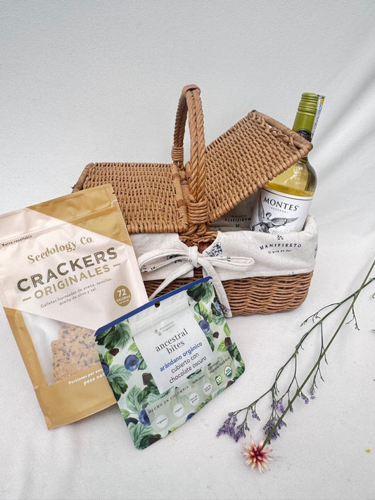 Canasta de picnic con vino tinto, chocolate con arándanos y crackers artesanales