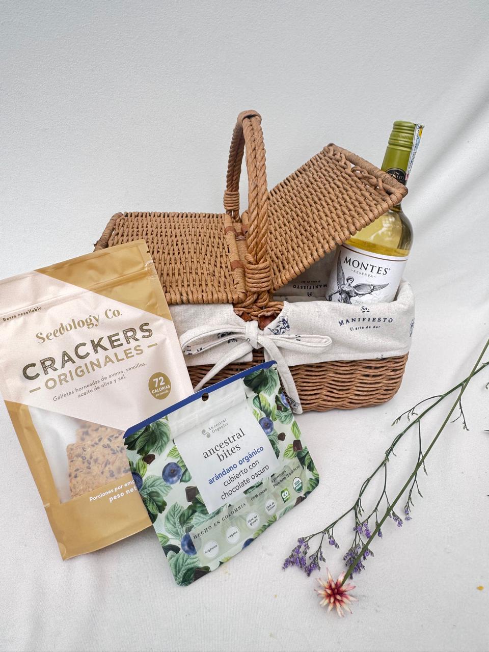 Canasta de picnic con vino tinto, chocolate con arándanos y crackers artesanales
